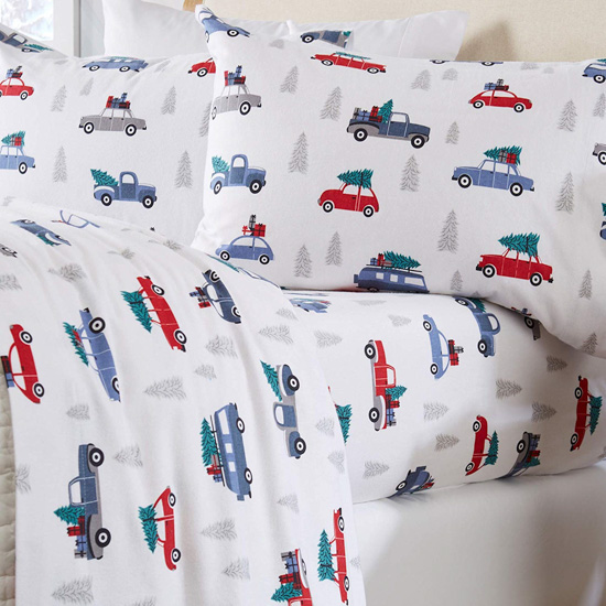 White flannel bedding covered with red and blue colored cars with Christmas trees tied to the top. 