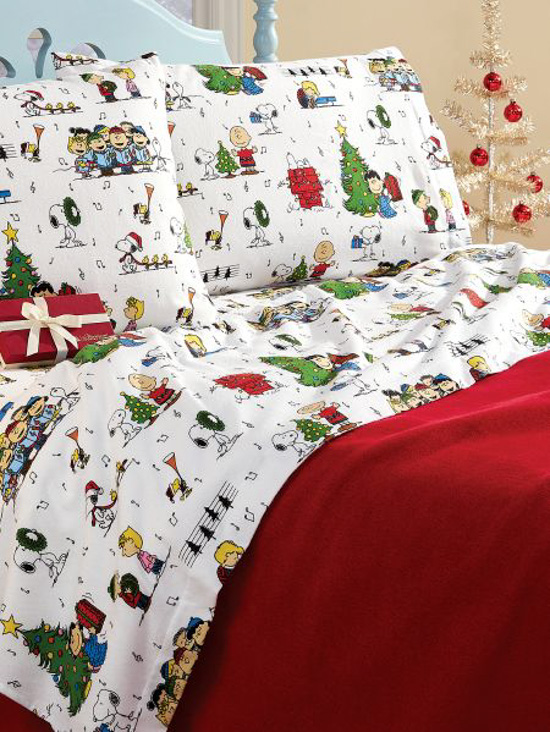 Light blue bed frame with a bed made up with a red comforter and caroling Peanuts characters on the flannel sheets. 