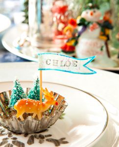 A place setting created by gluing trees, a deer and a name flag to the base.