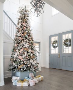 large flocked tree in a tall-ceilinged foyer with blue double doors.