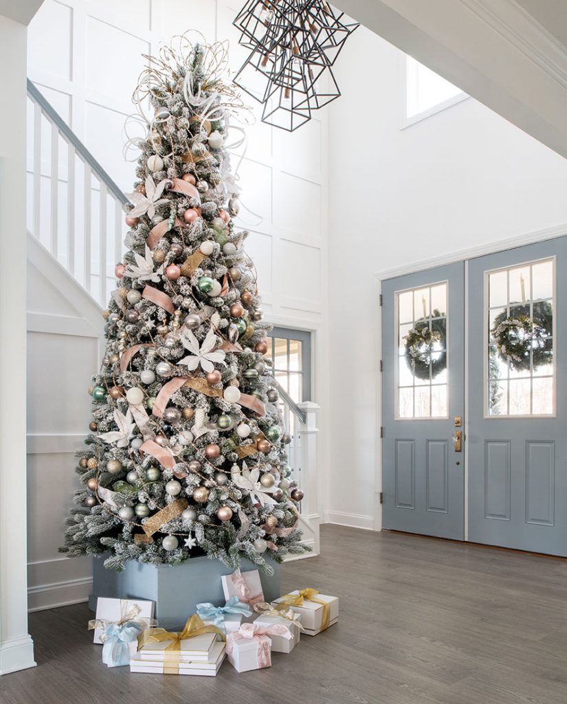 large flocked tree in a tall-ceilinged foyer with blue double doors.