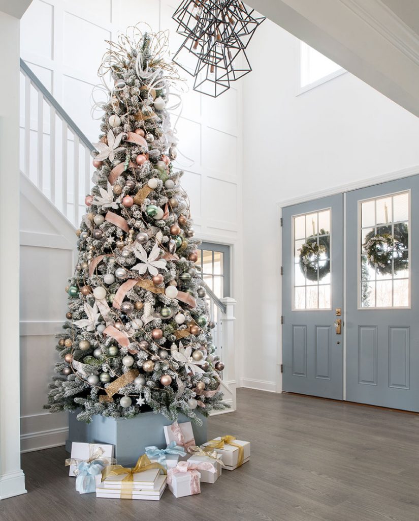 large flocked tree in a tall-ceilinged foyer with blue double doors. 