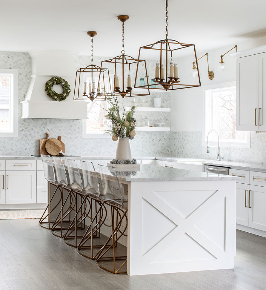 white kitchen with brass counter stools and large brass lantern-style pendants
