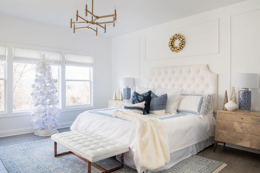 master bedroom with white tufted headboard and a brass modern chandelier