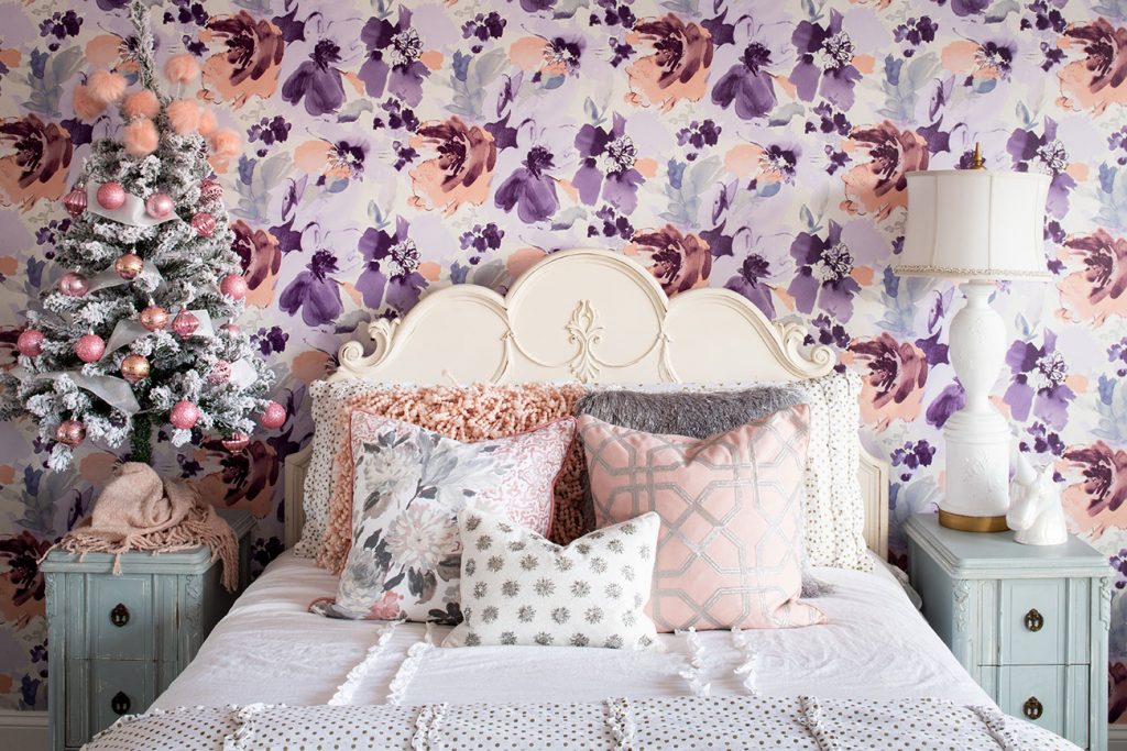 a young girls room with pink and purple floral wallpaper and a shabby white french style headboard