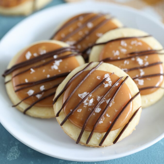 White plate with four salted caramel shortbread cookies on top.