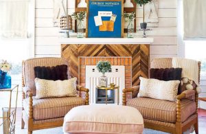 Living room with 2 armchairs and a restored shiplap and brick fireplace.