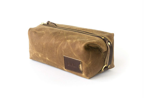 Personalized khaki toiletry bag with leather and zipper accents.