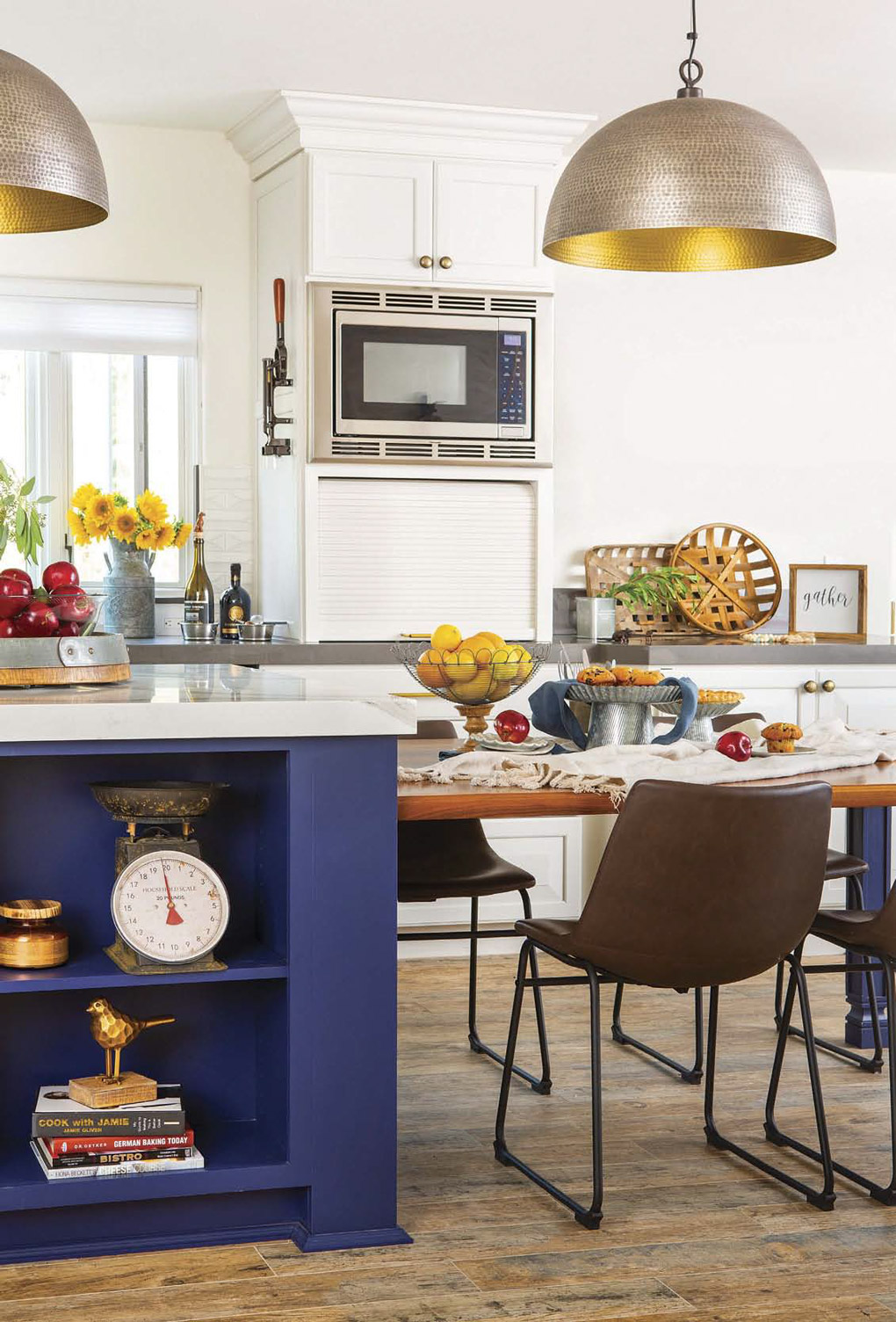 Kitchen remodel with Blue custom kitchen island with extended attached dining table under large rounded pendant lights 