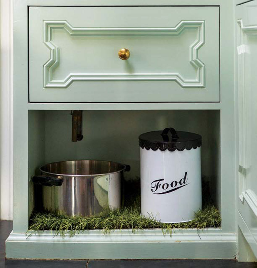 Light aqua kitchen cabinets with a creatively built-in dog feeding station. 