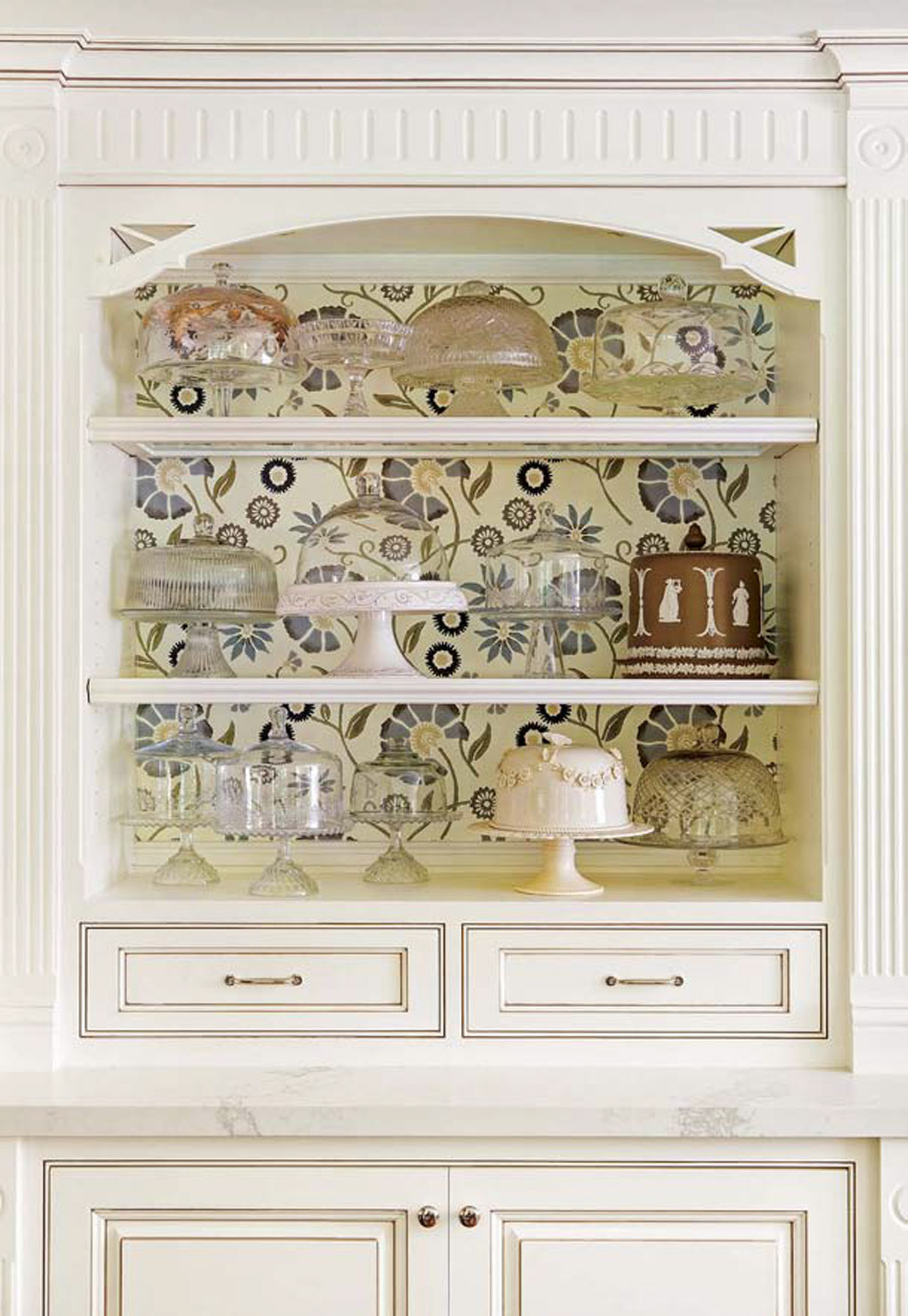 Cream colored accent cabinets with a custom display case filled with a collection of cake plates. 