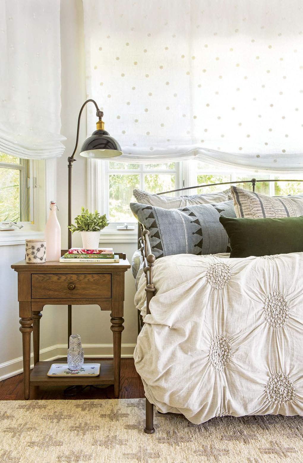 Guest room with an iron daybed next to an ornate bedside table topped with a lamp.