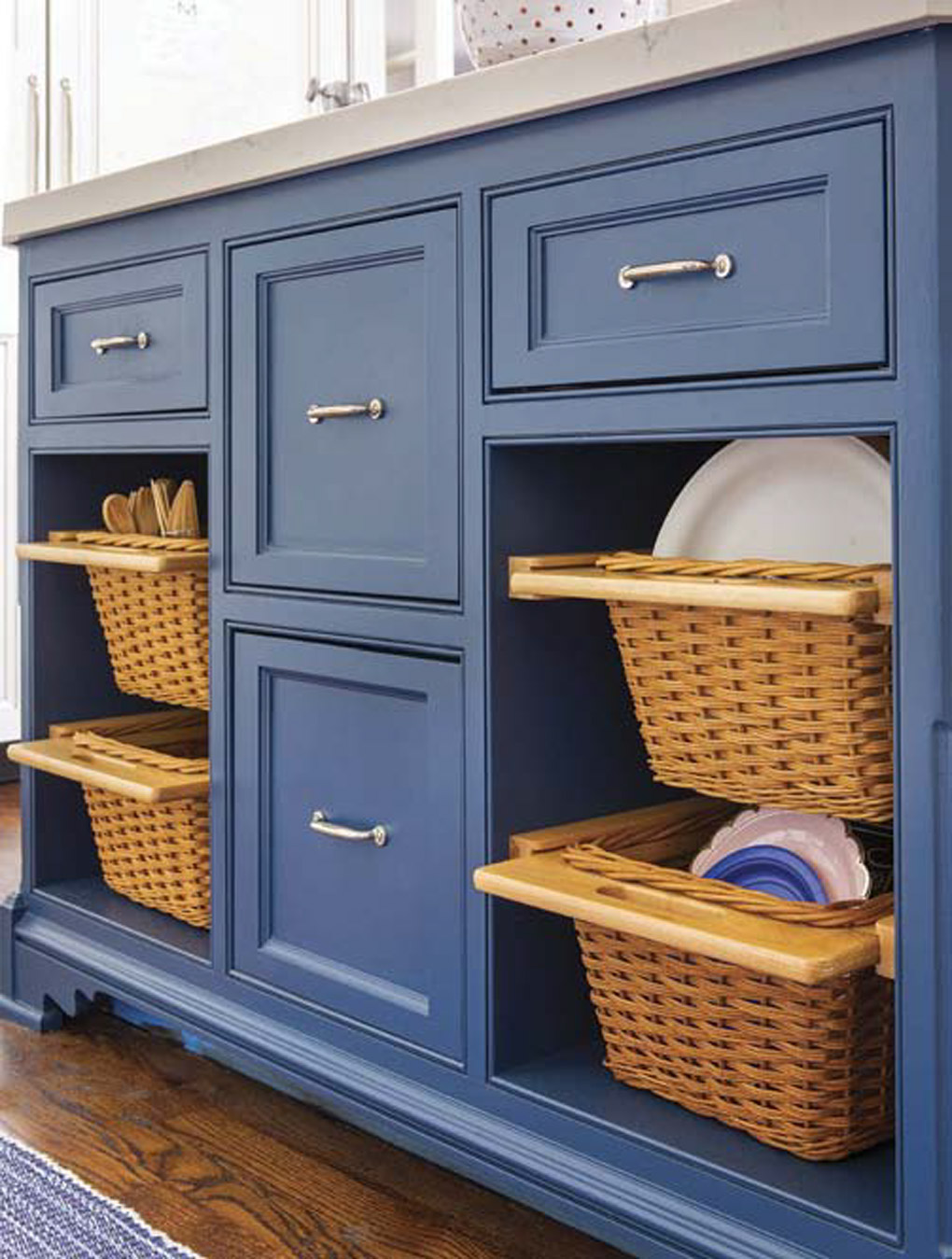 Blue lower cabinets with custom cutouts storing wicker storage baskets.