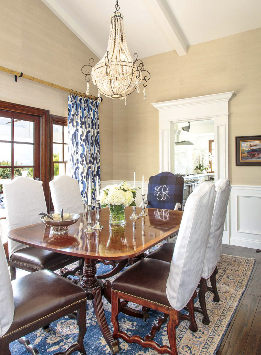 Regal British colonial formal dining space with a bright chandelier, double pedestal table and leather high-back chairs. 