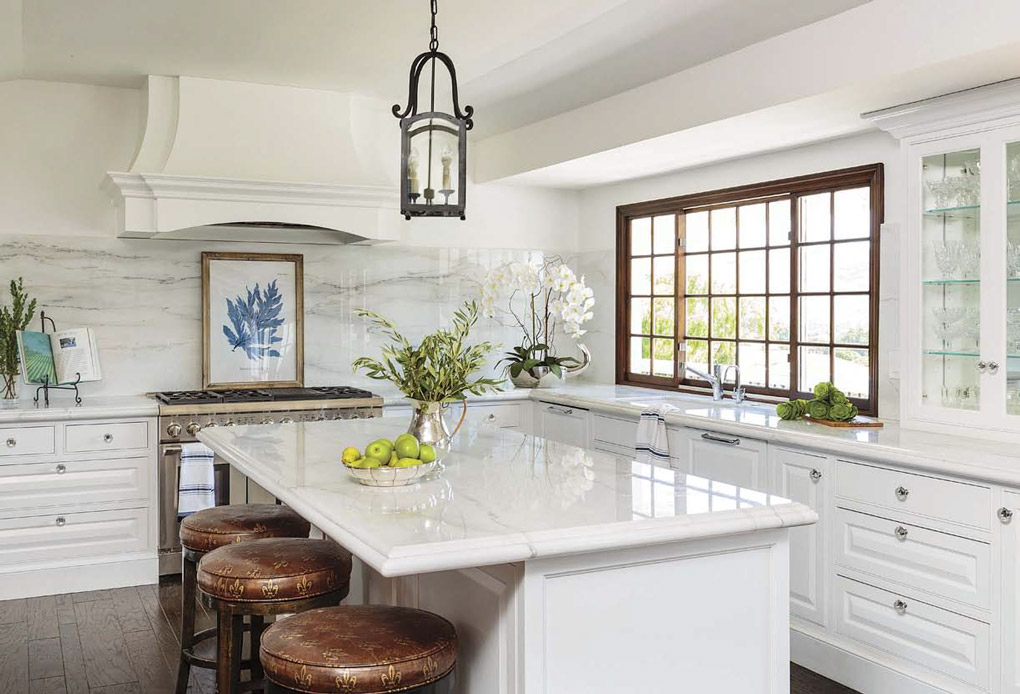 Welcoming home with an expansive all-white kitchen with marble counter and island tops and leather topped barstools.