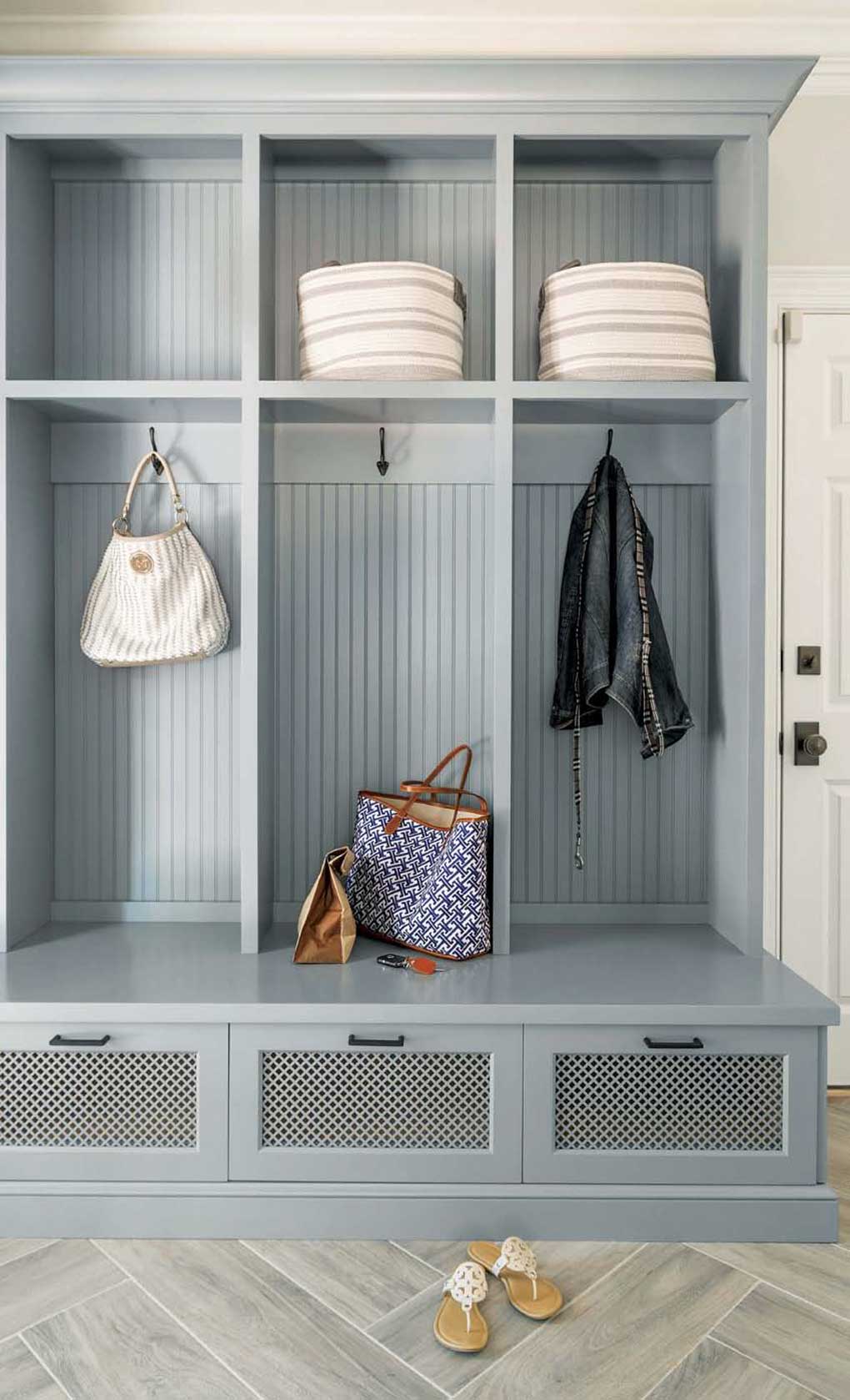 Gray blue colored builtin mudroom renovation with three separate personal spaces for folded, hanging and drawer items.