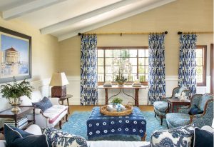 Living space with vaulted and beamed white ceilings and a British colonial styled living room with dark wooden and blue accents.