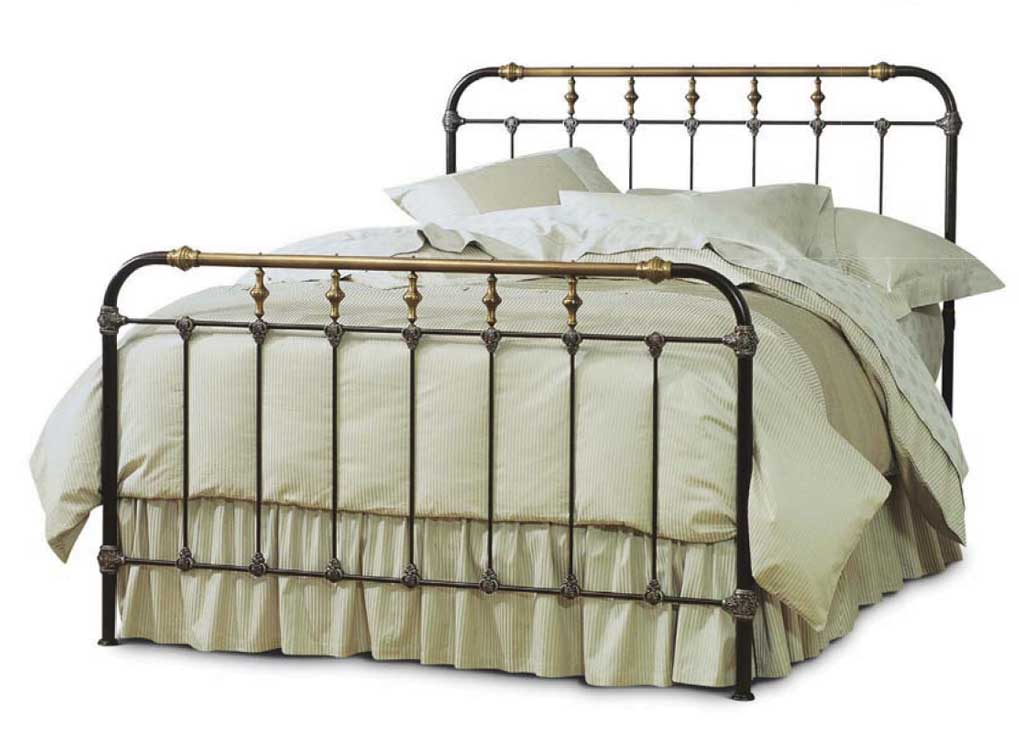 Iron and brass framework bed with beige linens.