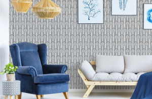 Art Deco patterned black and white wall paper in a living room with simple modern couch and classic blue velveteen armchair.