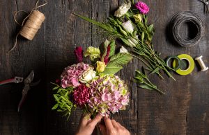 Overhead photograph of hands arranging flowers in a bouquet.