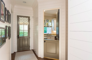 White shiplap walls and a Dutch-door with the top half open and looking into a laundry room.
