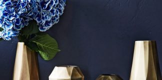 Gold geometric style vases in varying sizes, one filled with blue hydrangeas.