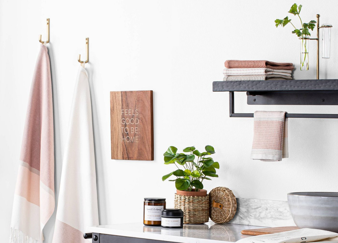 Kitchen counter with wooden rustic drawers and rose and cream colored hand towels on display alongside fresh greenery.