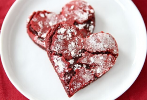 White plate with two heart shaped red and white crinkle-cookies.