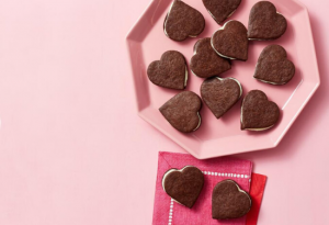 Pink octagonal tray covered in chocolate heart-shaped sandwich cookies.