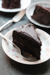 Slices of fudge chocolate cake on a china dessert plate with a silver fork.