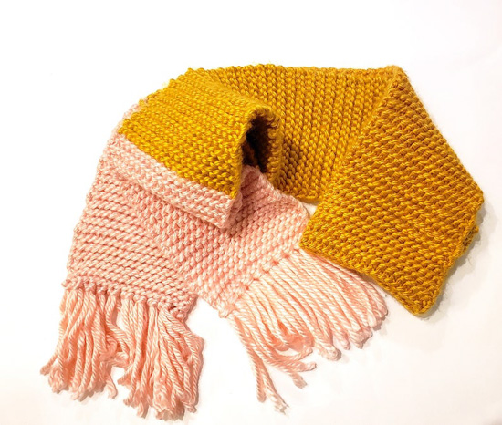 Two-tone scarf in pink and mustard yellow with fringe. 