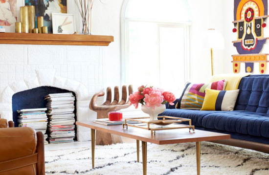 Mid-century modern living room with classic blue couch and vibrant hanging wall art featuring a color blocked throw pillow. 