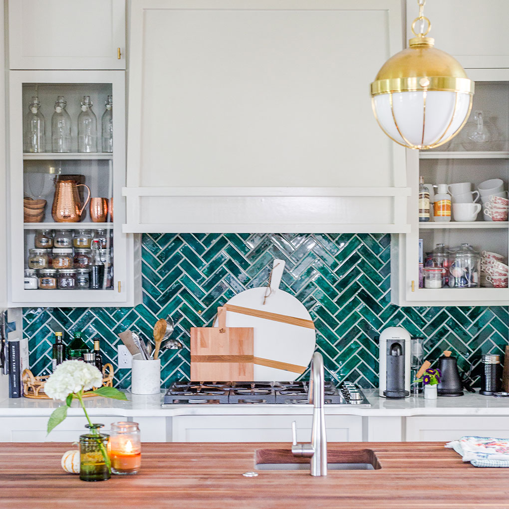 emerald green tile arranged in a herringbone pattern as a kitchen backsplash