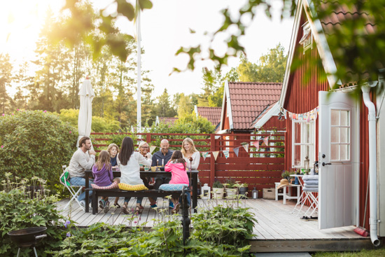 Clustered cottages lined up and a group of people sharing a meal on a back patio. 