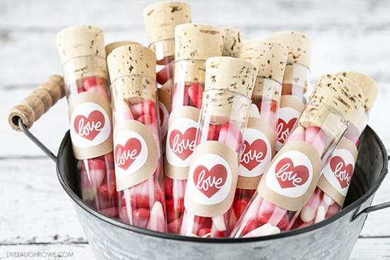 Galvanized metal container with wooden handles filled with corked tubes loaded with Valentine's treats.