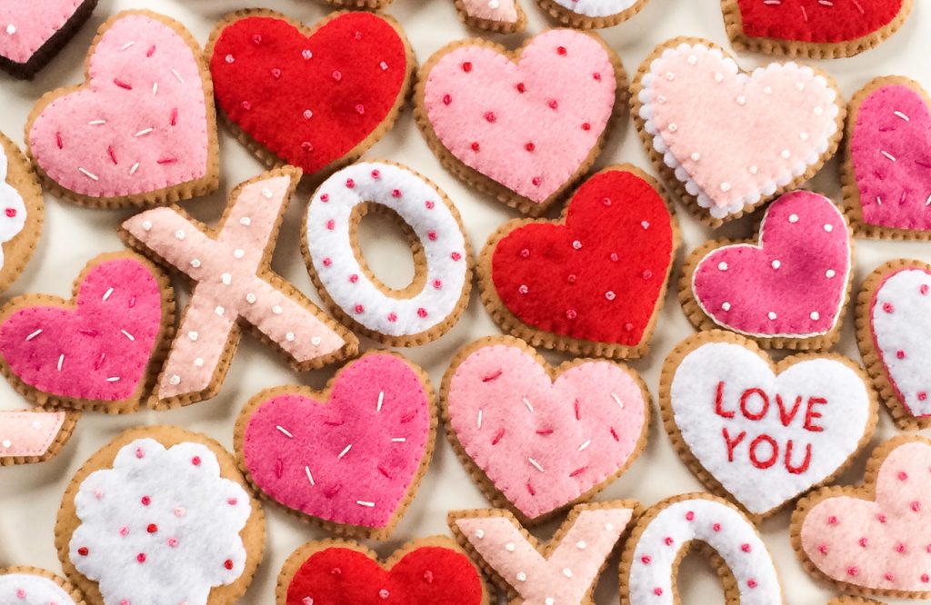 Overhead shot of Valentine's Crafts themed felt ornaments in the shapes of X's O's and hearts. 