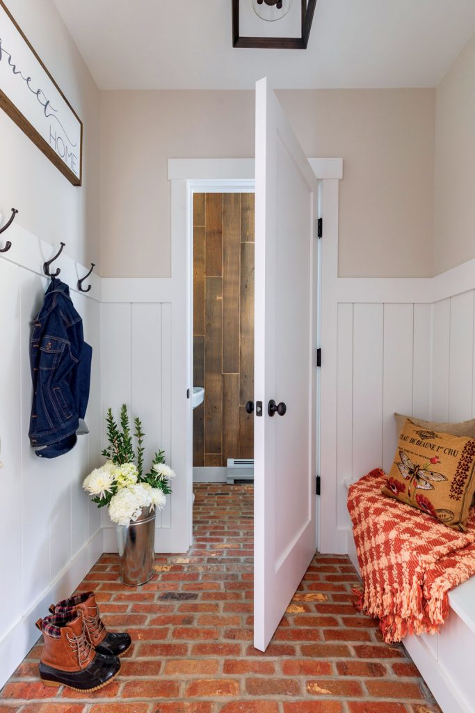 Entryway to a mudroom with white trim and red brick flooring. 