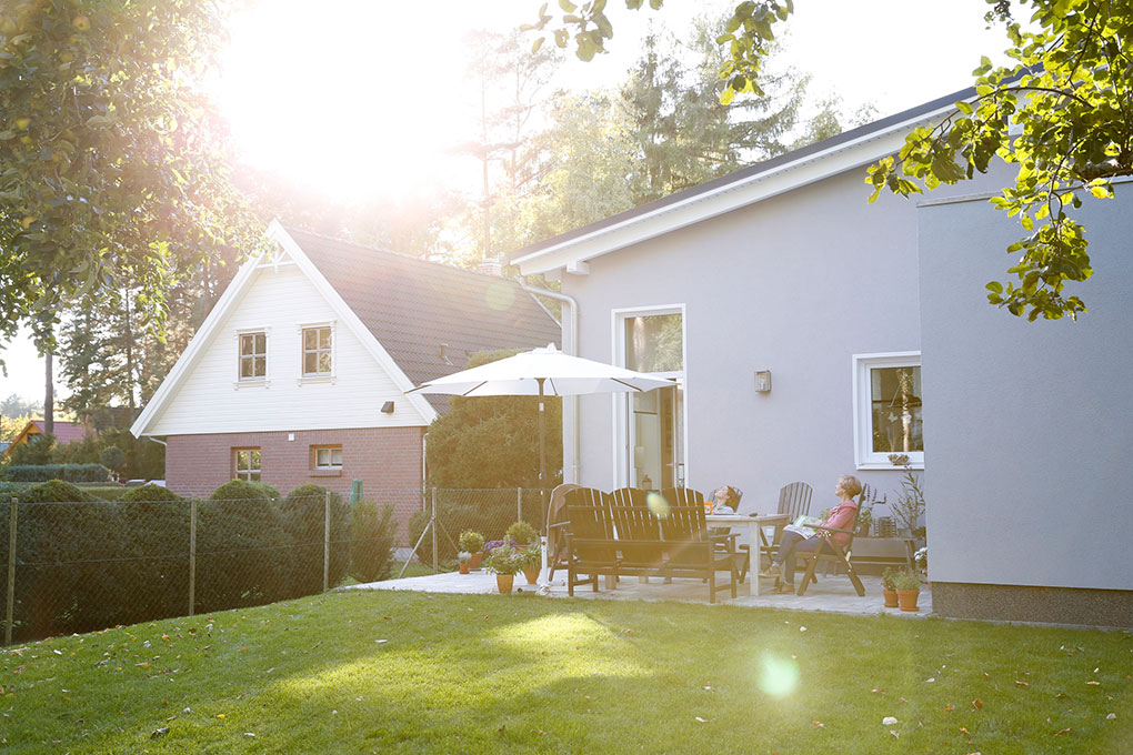 Sunflare streaking through a backyard as a woman sits in an Adirondack chair taking in the view. 