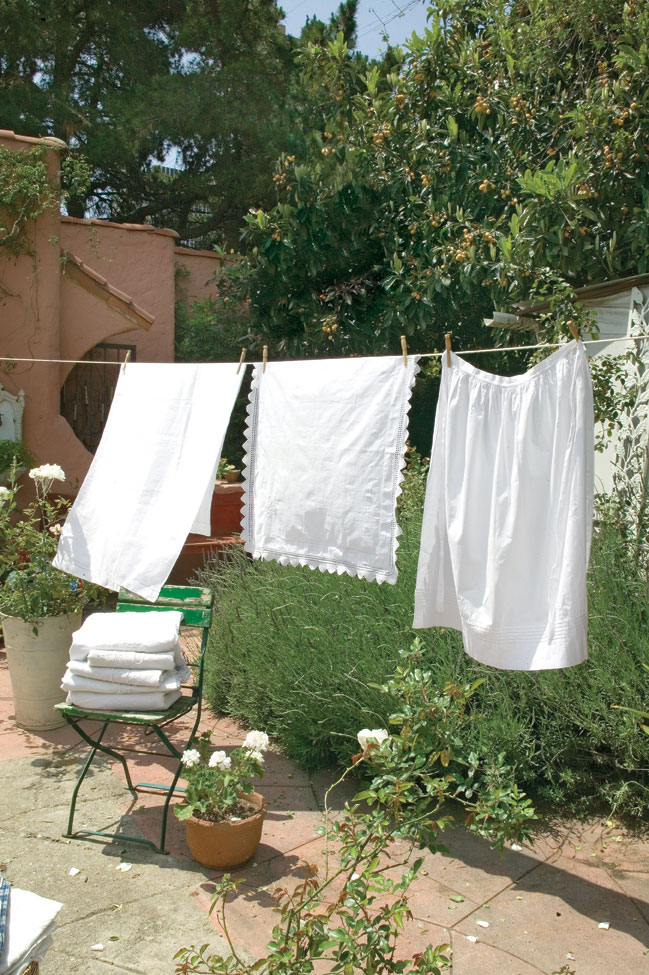 white french linens blowing in the breeze on a clothesline in the garden. Part of a home deep clean.