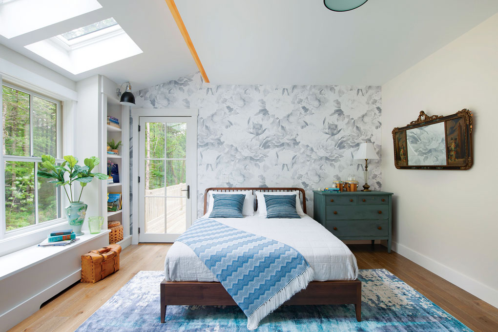 Master bedroom with cottage style blue and white accents and floral wallpapered accent wall behind the bed. 