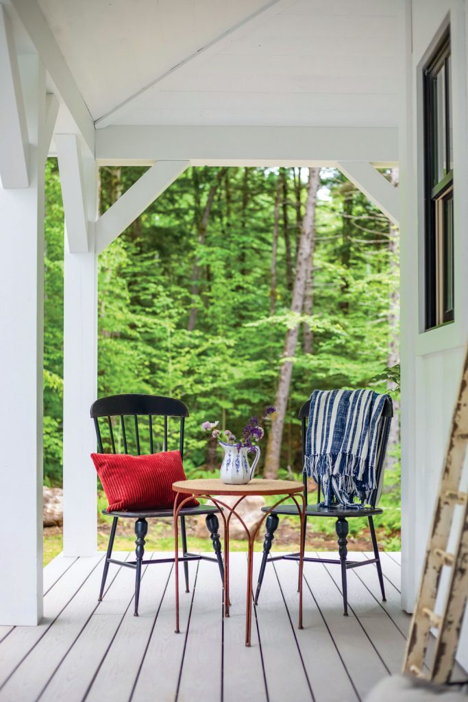 Gabled front porch with wood planks for flooring and a small bistro dining set.