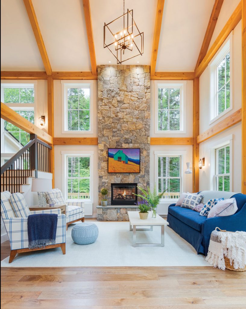 Great room with a farmhouse cottage feel. Large vaulted ceiling with wooden accent beams and blue and white cozy furniture. 