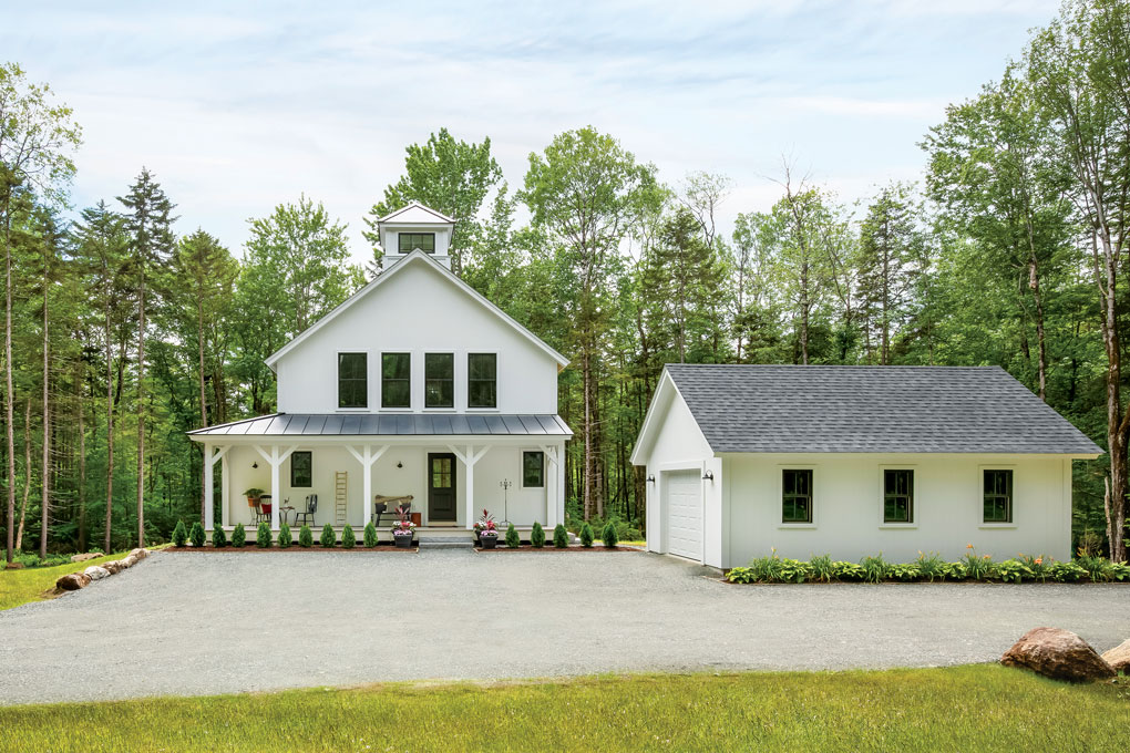 Exterior shot of the Springfield project house, a traditional farmhouse with a gabled porch and a detached garage. 