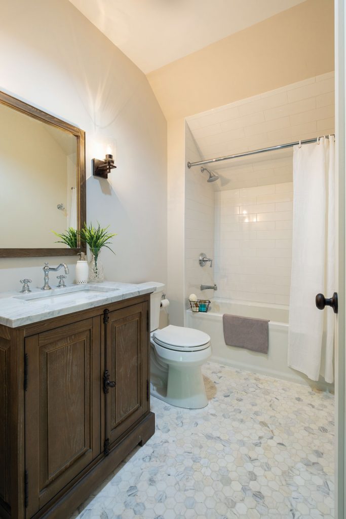 Master bathroom with custom wooden vanity and marbled, octagonal floor tiles.