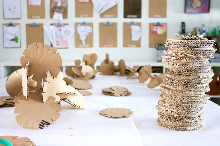 Homemade disc made of cardboard used to create sculptures placed on a table in an art room.