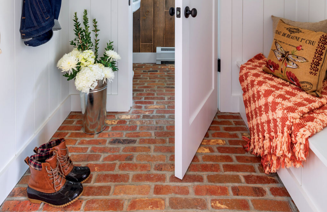 Entryway to a mudroom with white trim and red brick flooring.