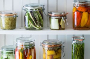 a variety of quick pickled vegetables in jars in a beadboard cabinet