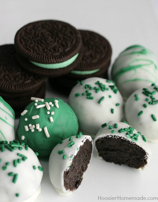 St. Patrick's Day Desserts Oreos with green frosting surrounded by Oreo truffles covered in green and white frosting and sprinkles.