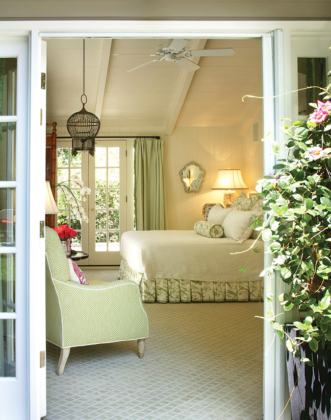 looking inside a sweet cottage bedroom through a garden door. Wisteria peeks in from the right as it frames the doorway. 