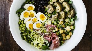 Composed mediterranean salad with eggs, artichokes, salami, potatoes and peas
